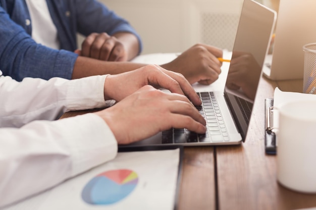 Équipe méconnaissable de jeunes hommes d'affaires travaillant sur ordinateur portable, tapant sur ordinateur, espace de copie