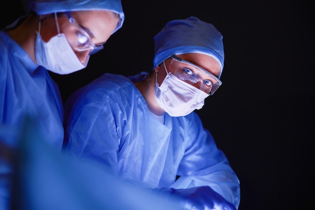 Équipe de médecins en chirurgie sur fond sombre