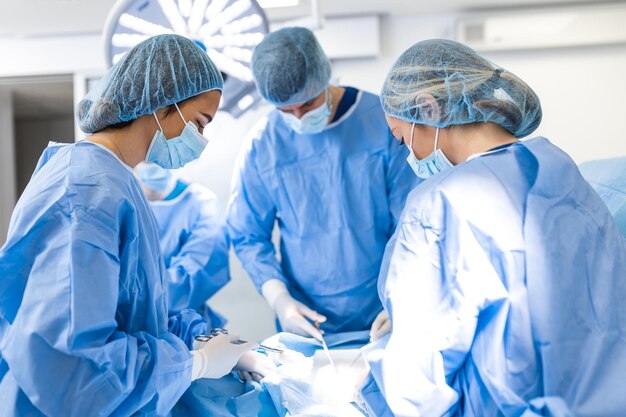 Équipe médicale effectuant l'opération Groupe de chirurgiens au travail dans la salle d'opération tonique en bleu Opération du médecin en salle d'opération à l'hôpital concept pour la publicité d'assurance