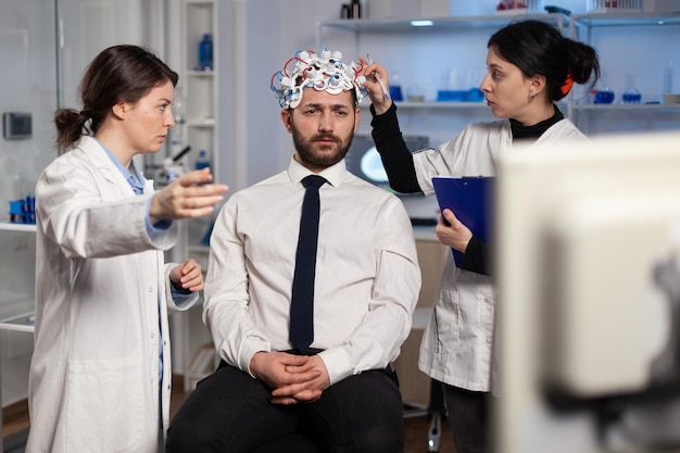 Équipe médicale de scientifiques ajustant l'eeg du cerveau analysant l'évolution du système nerveux d'un patient au cours d'une expérience de médecine dans un laboratoire de neurosciences. Médecin médecin surveillant l'activité de neurologie