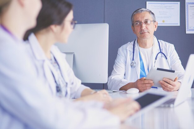 Équipe médicale sérieuse utilisant un ordinateur portable dans un bureau lumineux