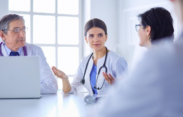 Équipe médicale sérieuse utilisant un ordinateur portable dans une salle de consultation lumineuse