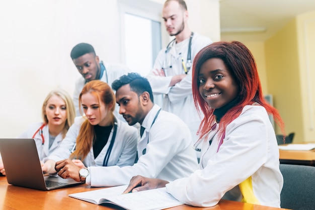 Équipe multiraciale de jeunes médecins travaillant sur ordinateur portable en cabinet médical.