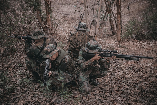 Équipe de soldat de l'armée avec mitrailleuse se déplaçant dans la forêtSoldat de la milice thaïlandaise en uniforme de combat dans le boisPromenez-vous la patrouille en pente dans la forêt tropicale