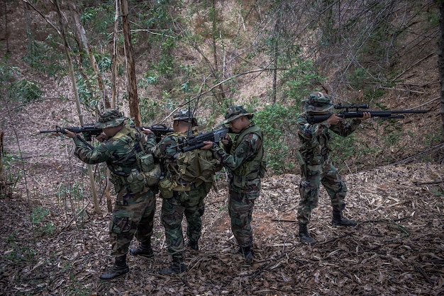 Équipe de soldat de l'armée avec mitrailleuse se déplaçant dans la forêtSoldat de la milice thaïlandaise en uniforme de combat dans le boisPromenez-vous la patrouille en pente dans la forêt tropicale