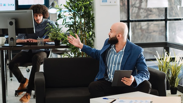 Équipe de start-up discutant d'une nouvelle vision, vérifiant les rapports annuels de données pour aider à la recherche d'un nouveau projet d'investissement. Partenaires commerciaux examinant les statistiques officielles, espace de coworking. Tir au trépied.