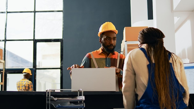 Équipe de travailleurs parlant de boîte de produits dans le dépôt, vérifiant les colis et les conteneurs dans la salle de stockage. Groupe de personnes travaillant sur le contrôle de la qualité avec des marchandises sur des racks. Prise de vue à main levée.