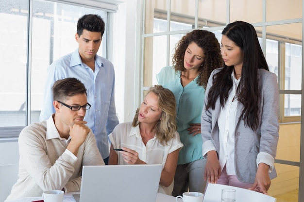 Équipe de vêtements de travail ayant une réunion en utilisant un ordinateur portable