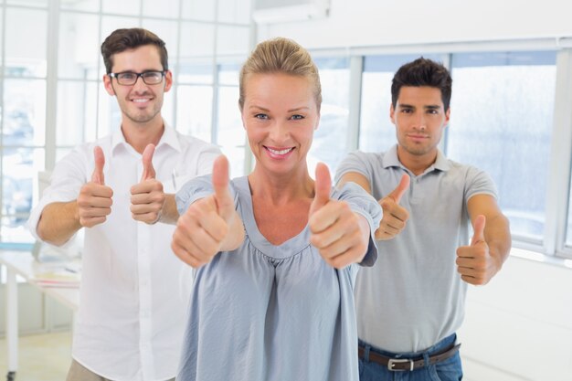 Équipe de vêtements de travail souriant à la caméra avec les pouces vers le haut