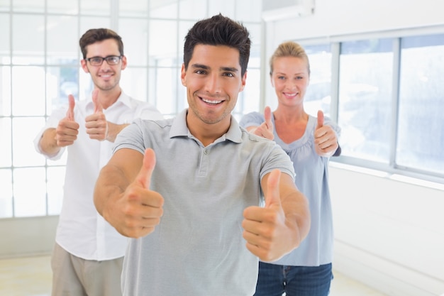 Équipe de vêtements de travail souriant à la caméra avec les pouces vers le haut