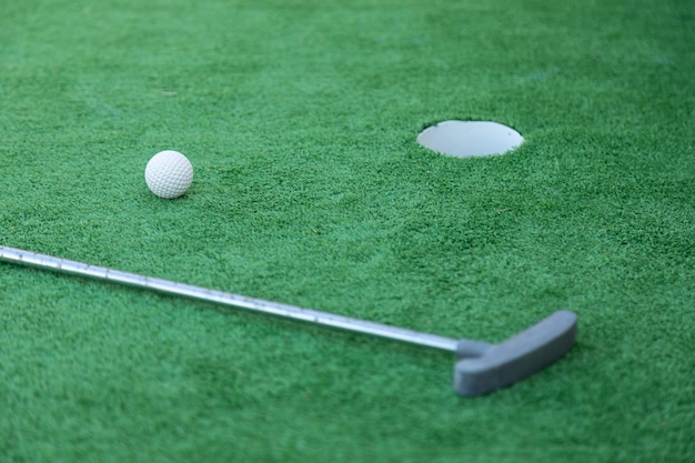 Équipement de mini-golf, club de golf, balle et trou sur terrain vert