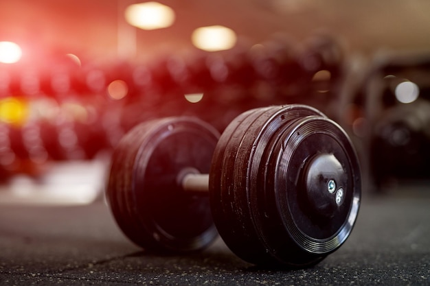 Équipement de sport dans la salle de gym Haltères sur le sol Image en gros plan d'un équipement de fitness dans la salle de gym Poids de gym à la lumière