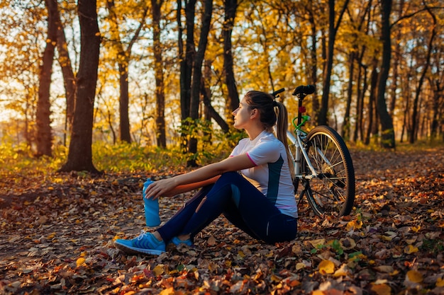 Équitation, vélo, dans, automne, forêt, jeune femme, reposer, après, entraînement, sur, vélo, style de vie sain