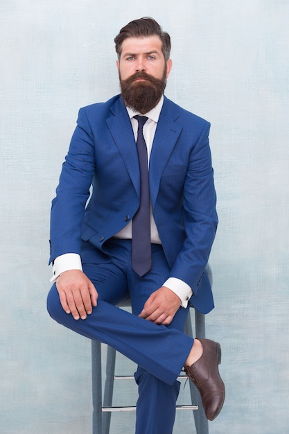 Équité et justice. Classe et formel. L'homme barbu porte un costume formel. Un avocat élégant est assis sur une chaise. Réunion d'affaires. Événement formel. Homme avec barbe et moustache avocat confiant. Votre avocat.