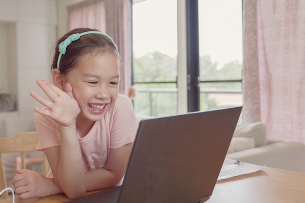 Race Mixte Jeune Fille Asiatique Faisant Des Appels Vidéo Facetime Avec Un Ordinateur Portable à La Maison, En Utilisant L'application D'apprentissage En Ligne Zoom, La Distanciation Sociale, L'isolement, L'éducation à Domicile, L'apprentissage à Distance Concept