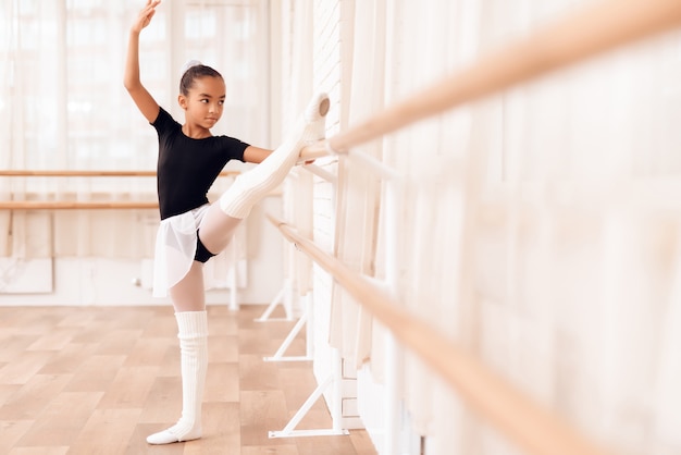 Race mixte Kid s&#39;étire près de Ballet Barre.