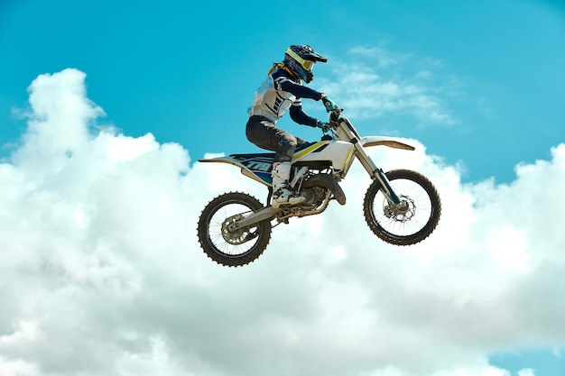 Racer sur moto dirtbike motocross crosscountry en vol saute et décolle sur tremplin contre sky Concept repos extrême actif