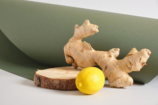 Racine de gingembre, citron et support en bois sur fond gris et vert, maquette de fond cosmétique
