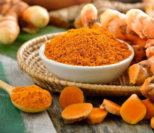 Racines de curcuma dans le panier sur la table en bois