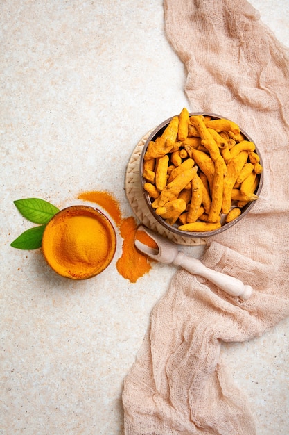 Racines de curcuma séchées et poudre avec des feuilles sur fond clair vue de dessus à plat