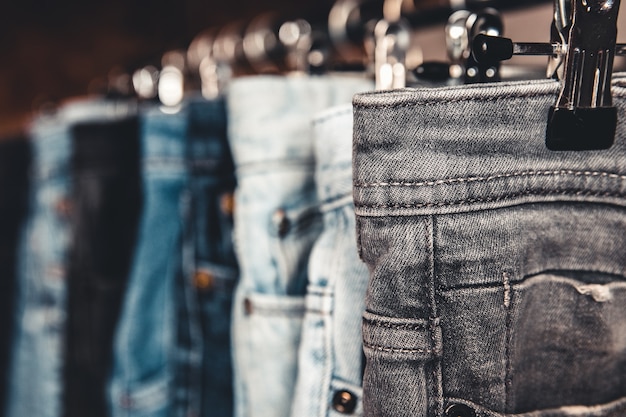 Rack avec différents jeans sur fond gris