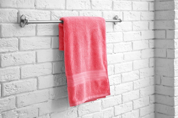 Rack avec une serviette douce et propre sur un mur de briques