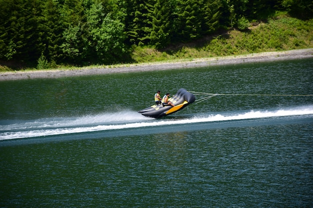 Un radeau de sport gonflable avec deux hommes flotte rapidement dans l'eau et s'en détache presque