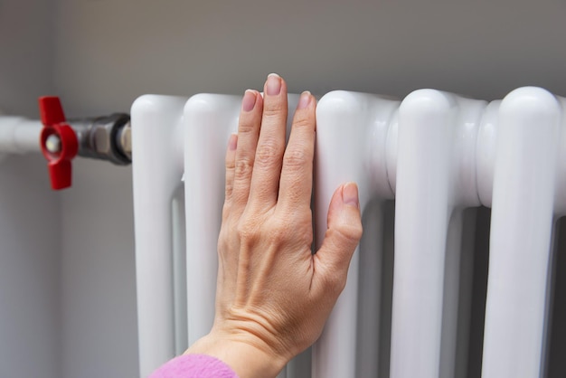 Radiateur avec une main chauffée dessus Économiser de l'argent crise économique hausse des prix