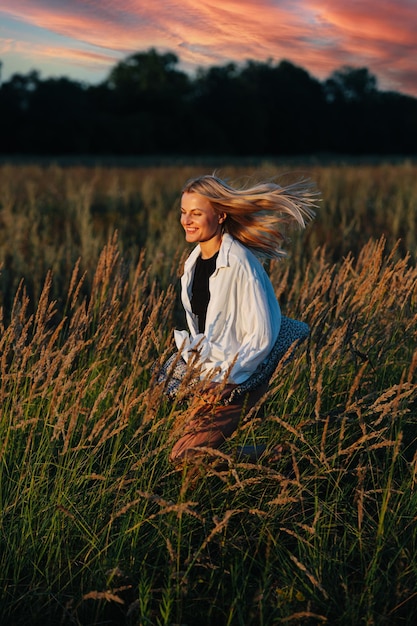 Radieuse jeune femme blonde qui traverse un champ de blé