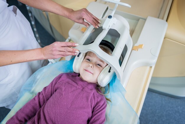 Le radiologue prépare la petite fille à un examen cérébral par IRM.
