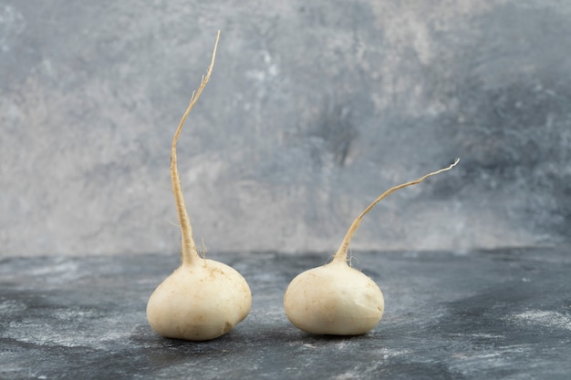 Radis blancs entiers placés sur une table en marbre.