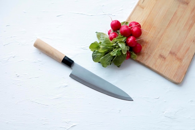 Radis frais et grand couteau de cuisine sur fond blanc et vieille planche à découper en bois. espace de copie