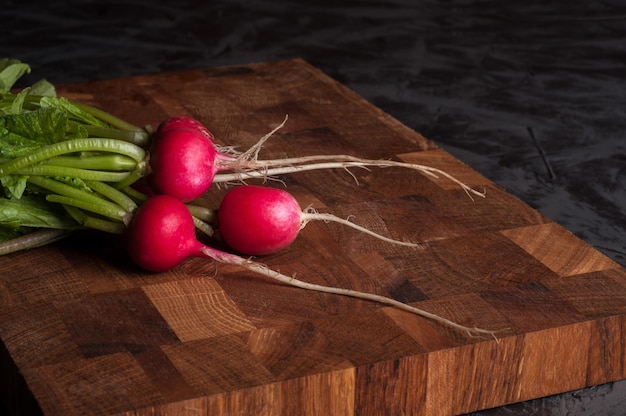 Radis sur une planche de bois sur fond sombre