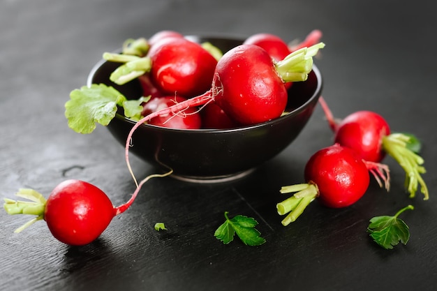 Radis rouge cru frais dans la plaque sur le fond en bois noir