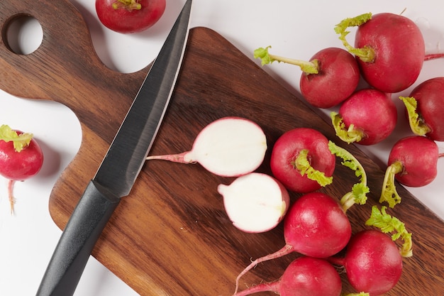 Radis rouge frais sur une planche à découper. Ensemble de radis de jardin tout petit frais isolé sur une surface blanche. Vue de dessus. Mise à plat. fraîchement cueilli dans un jardin biologique de croissance à domicile. Concept de nourriture.