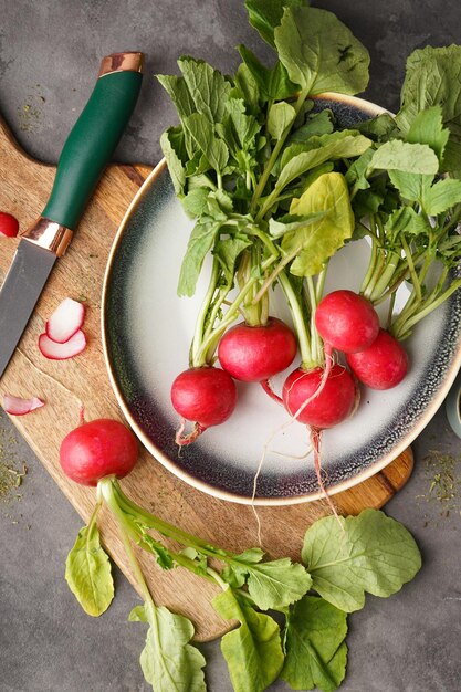 Radis rouge mûr dans un bol sur fond gris à plat Radis rouge frais verticalement