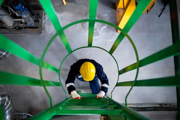 Raffinerie ou travailleur industriel dans l'équipement de sécurité grimpant sur des échelles ou des escaliers métalliques