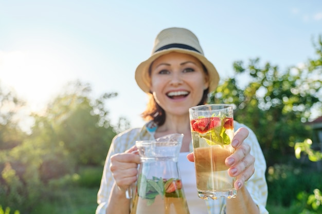 Rafraîchissements printemps été, femme dans la nature tenant un pot de menthe fraise et citron