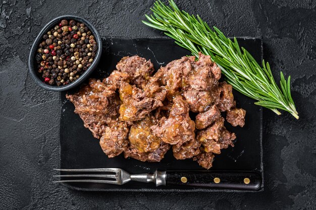 Ragoût d'agneau et de viande de boeuf sur un plateau en marbre. Fond noir. Vue de dessus.