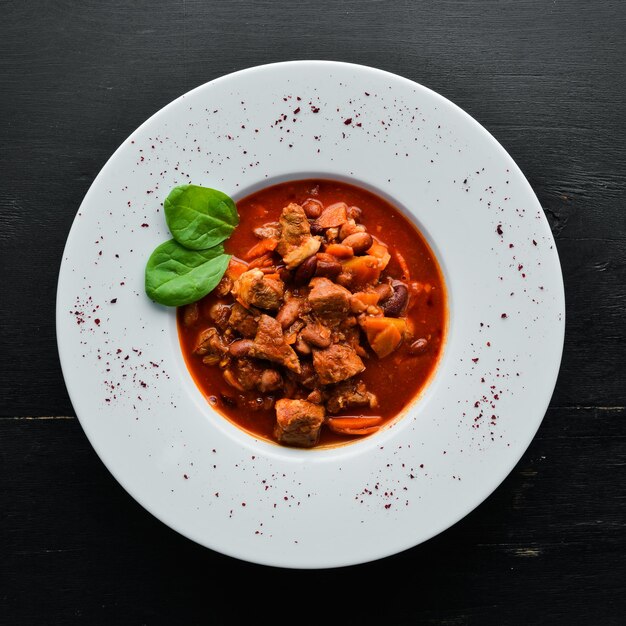 Ragoût de boeuf aux haricots et légumes dans une sauce tomate sur une assiette. Vue de dessus. Espace de copie gratuit.