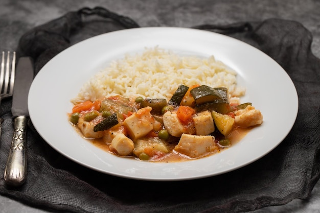 Ragoût de calamars aux légumes et riz bouilli sur assiette