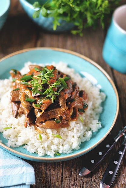 Ragoût de foie dans une sauce aux oignons, carottes et persil et riz bouilli