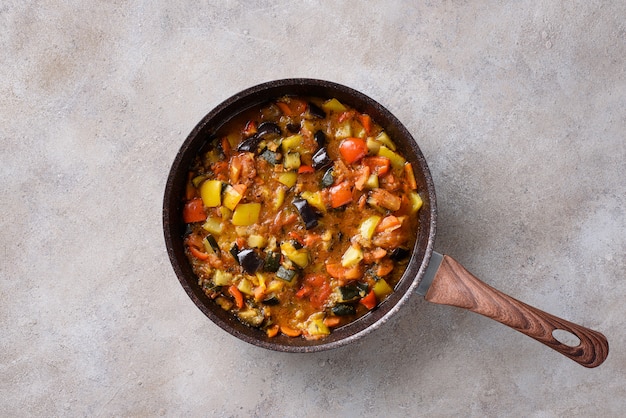 Ragoût de légumes dans une casserole: aubergine, tomates, poivrons, courgettes, oignons, huile d'olive, épices. Plat végétalien.