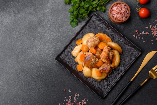 Ragoût de viande de boeuf et de légumes sur une plaque noire avec pommes de terre rôties