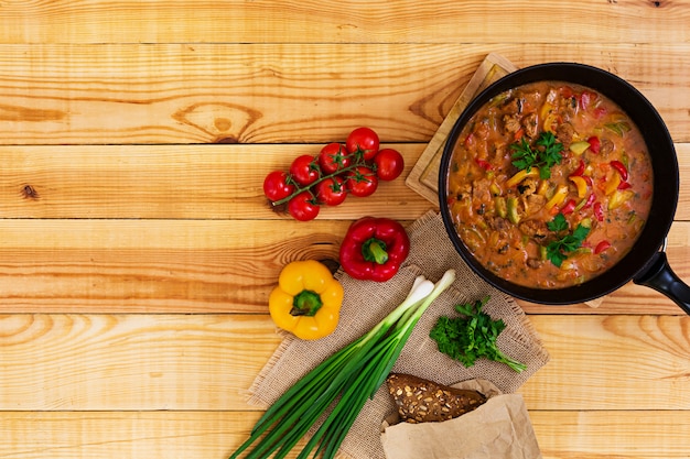 Ragoût de viande et de légumes à la sauce tomate sur bois. Vue de dessus