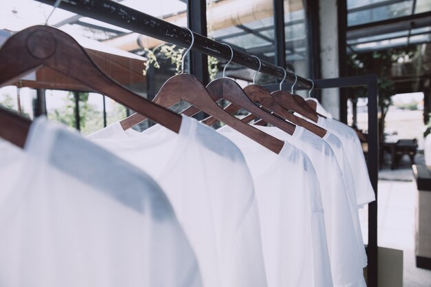 Rail avec des t-shirts blancs sur des cintres dans le magasin. Vêtements d'été décontractés