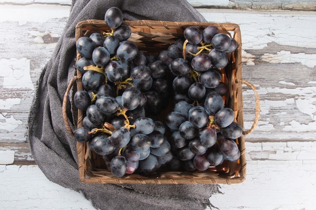 Raisin de fruits violets dans un panier sur une surface en bois vieilli.