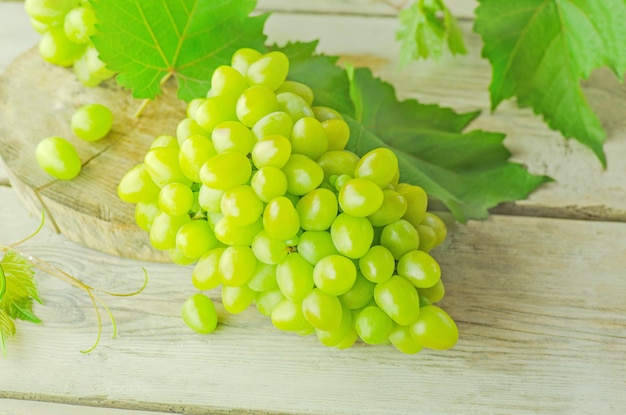 Raisin vert doux sur le fond en bois Raisins verts frais Grappe de raisin et feuille de vigne Vue de dessus mise à plat