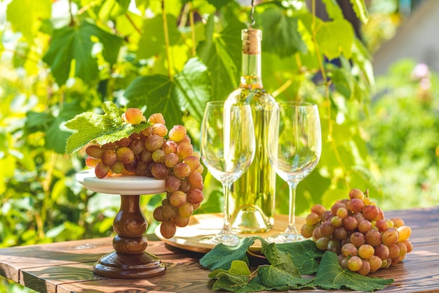 Raisin et vin blanc Raisin vert et vin blanc dans le vignoble Grappe de raisin avec des gouttes d'eau sur la table Jardin ensoleillé avec fond de vignoble