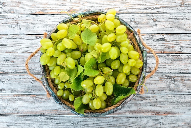 Raisins blancs dans une boîte en bois sur une table en bois blanche Feuilles de raisin Vue de dessus Espace libre pour le texte